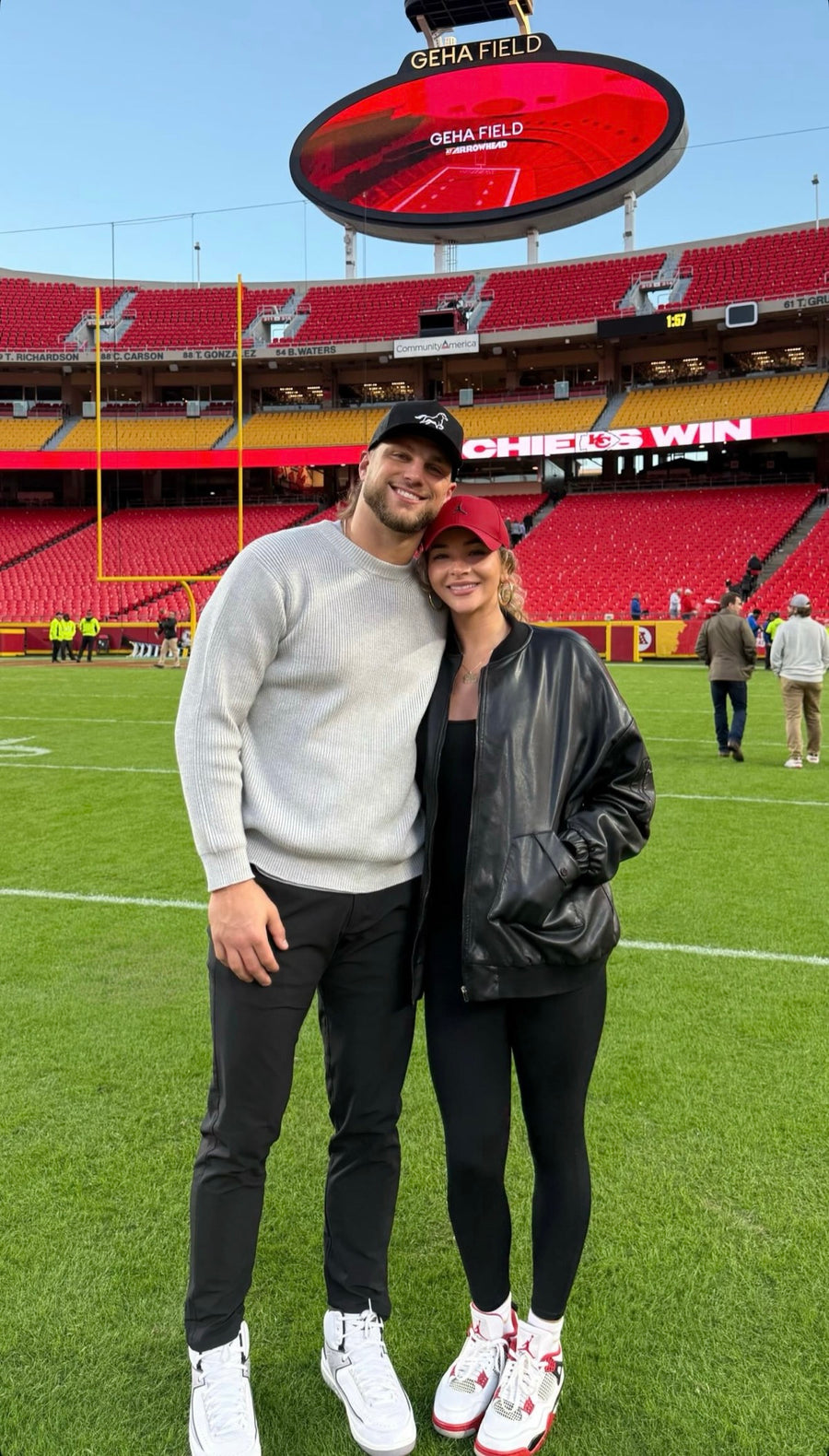 Two friends on a football field, one wearing a black Stally horse cap.