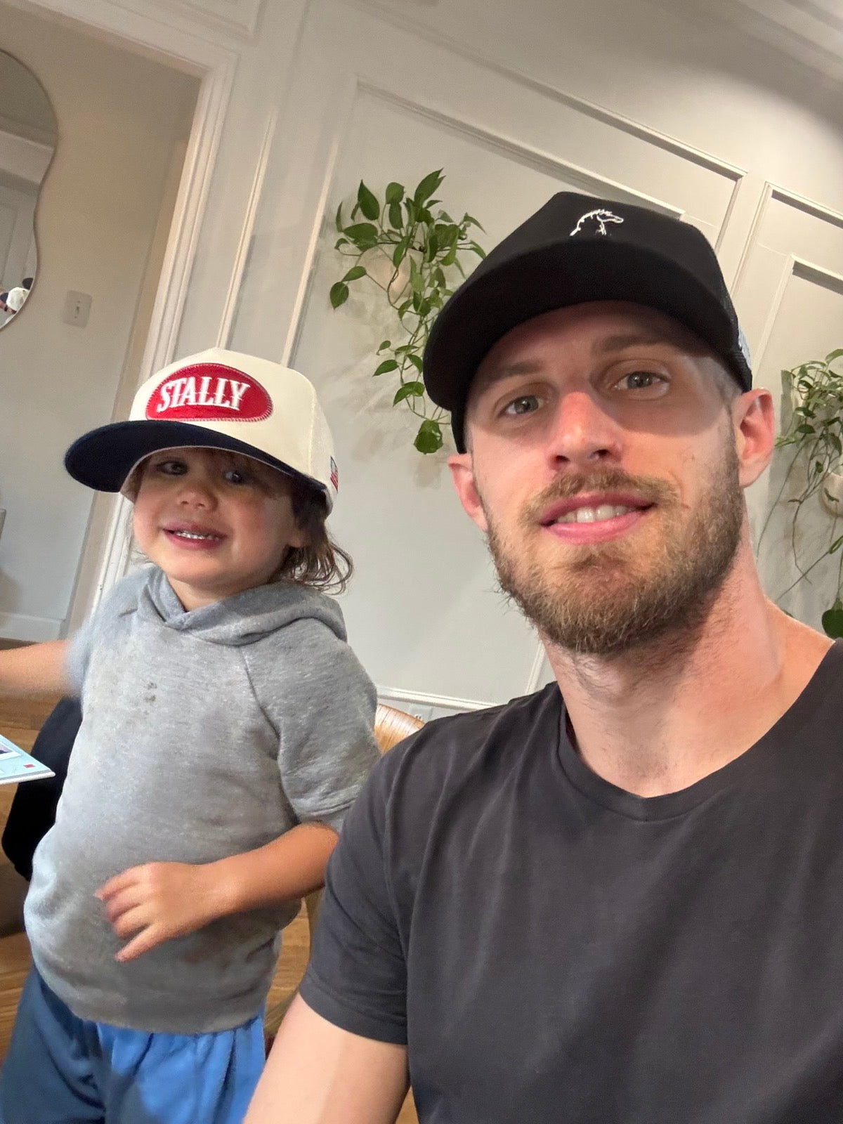 Man and child wearing an All American STALLY hat and an OG STALLY hat sitting indoors