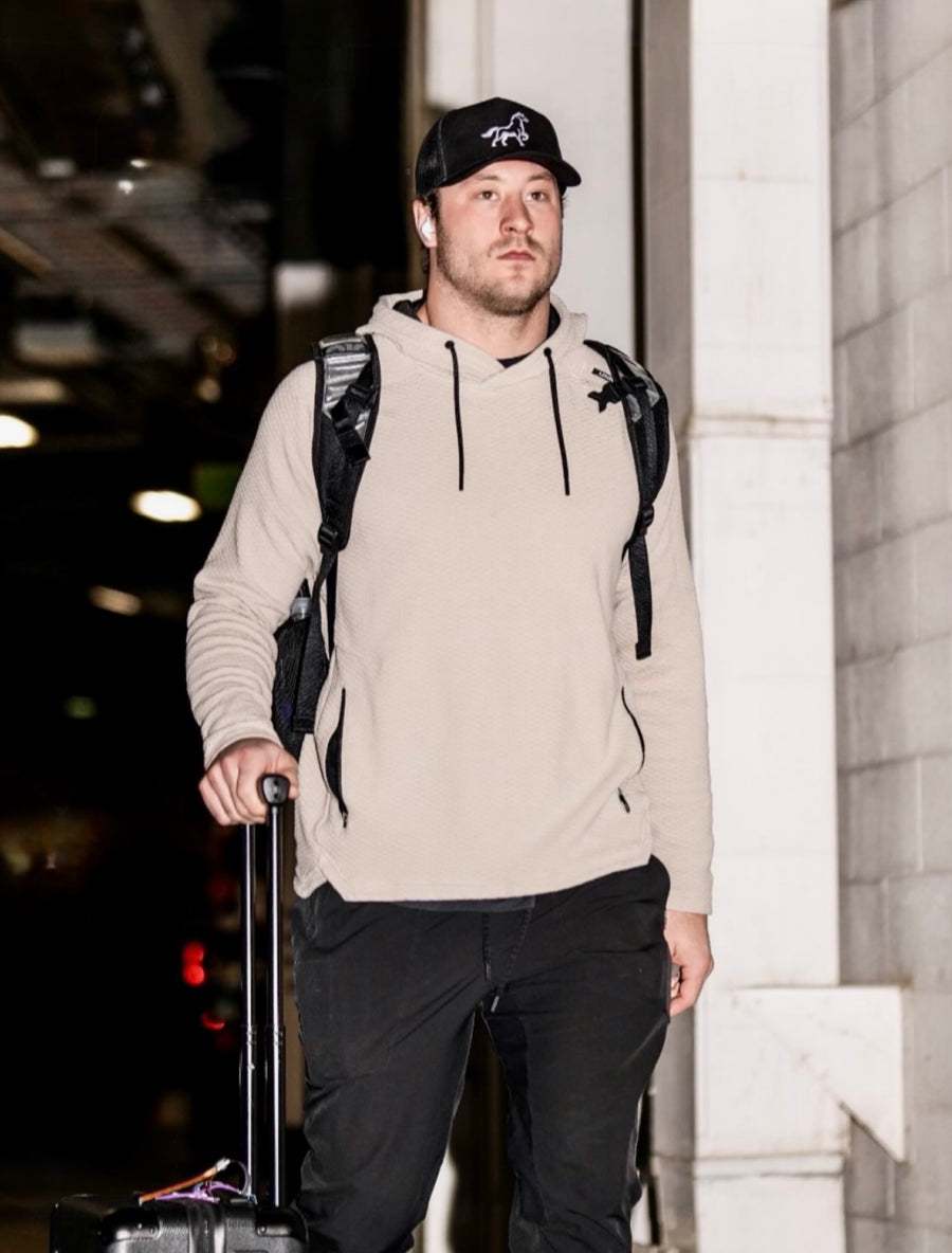 A traveler in a black Stally horse cap carrying a backpack and rolling luggage.