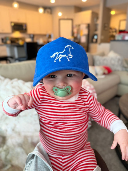 Baby wearing a Blue OG STALLY hat and red and white striped outfit in a living room.