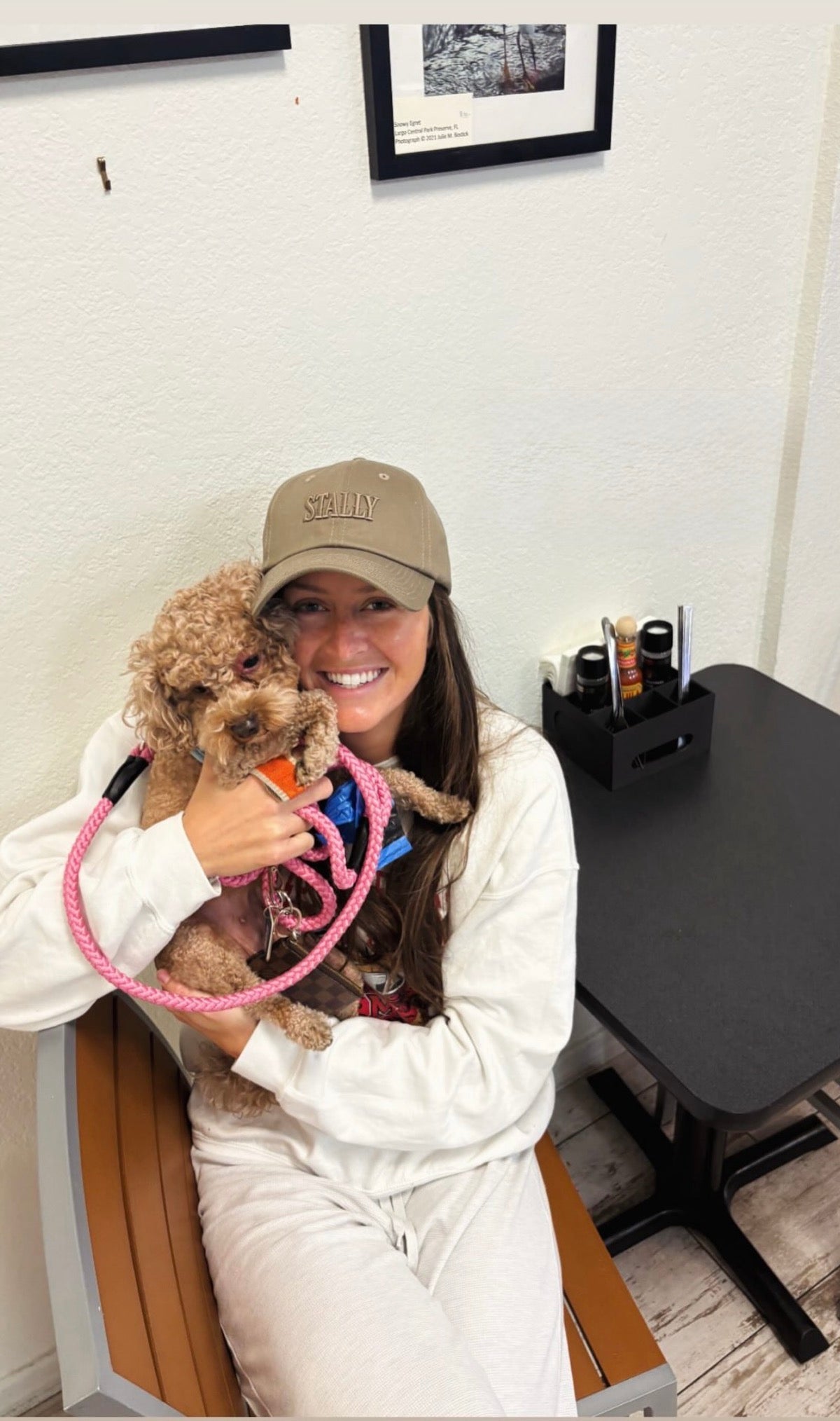 Person holding a small dog in an office setting wearing a STALLY Heritage Dad Hat