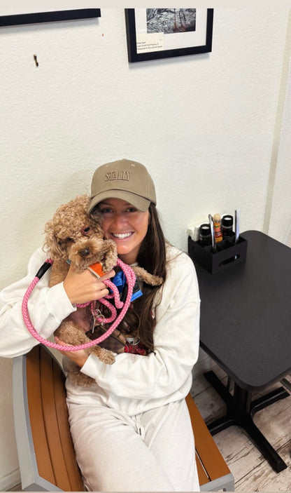 Person holding a small dog in an office setting wearing a STALLY Heritage Dad Hat
