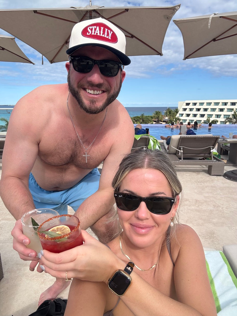 Man and woman by a poolside with the man wearing an All American STALLY hat.