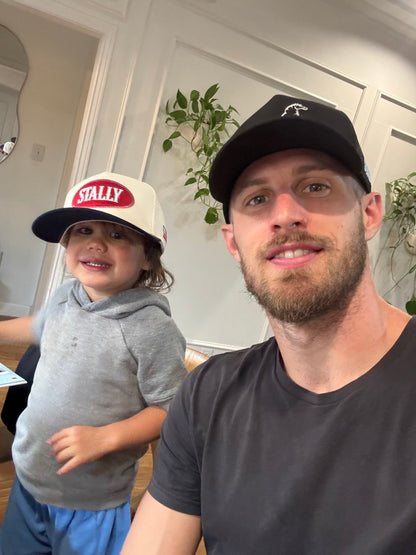 Man and child wearing an All American STALLY hat and an OG STALLY hat sitting indoors