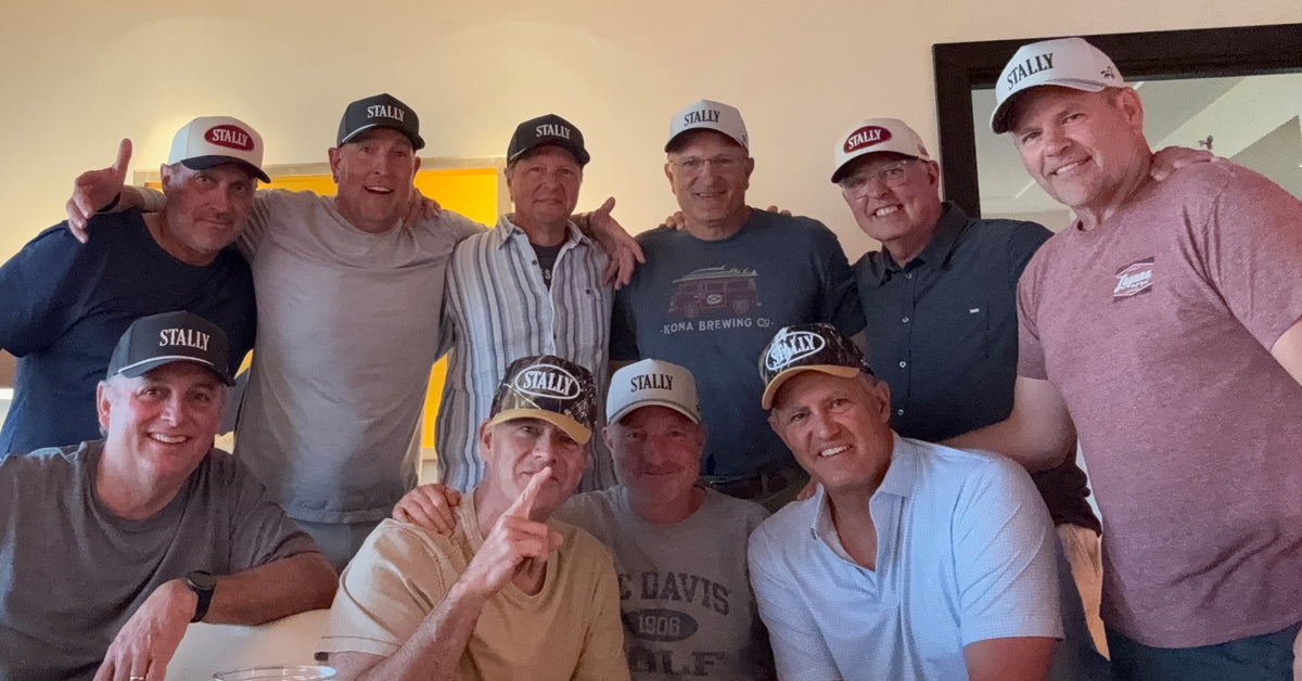 A group of men in Stally caps, arms around each other, smiling for a photo