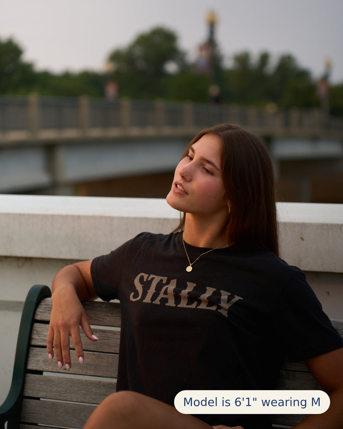 Stally Workhorse Performance Tee in Coal Black seated on a park bench