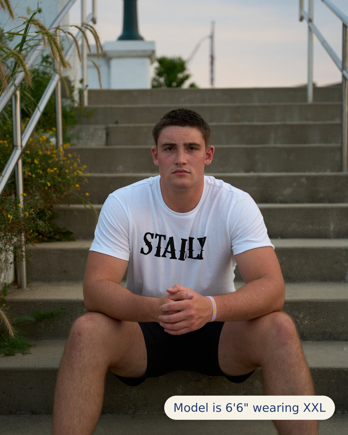 Stally Workhorse Performance Tee in Chalk White seated on outdoor steps