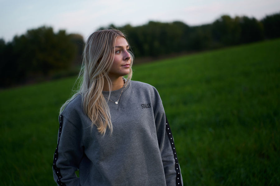 A woman in a Grey Heather Stally Range women's boxy crew in a green field